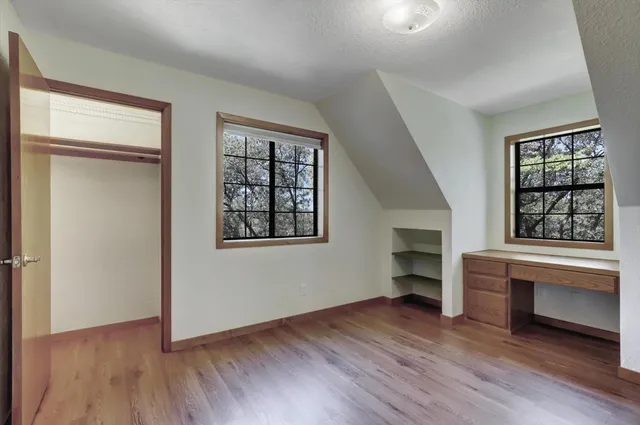 an empty room with wooden floor closet and windows