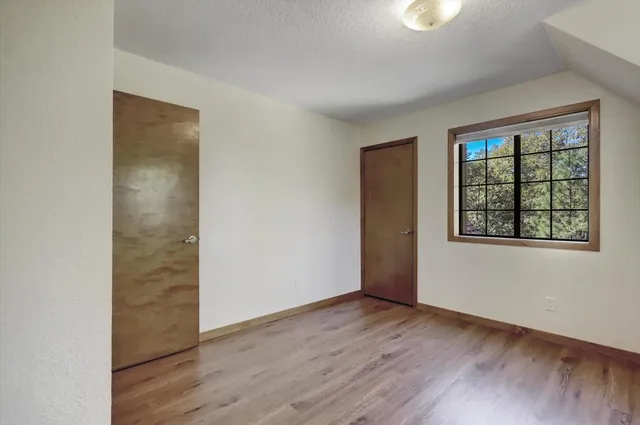 a view of an empty room with a window and wooden floor