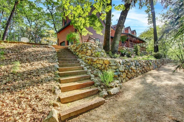 a backyard of a house with large trees and outdoor seating