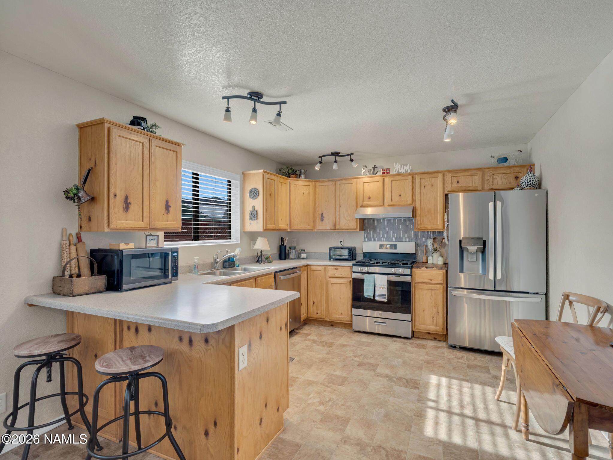 1105 West Morse Avenue Williams, AZ 86046 - Photo 7 of 26 a kitchen with granite countertop a table chairs stove and refrigerator