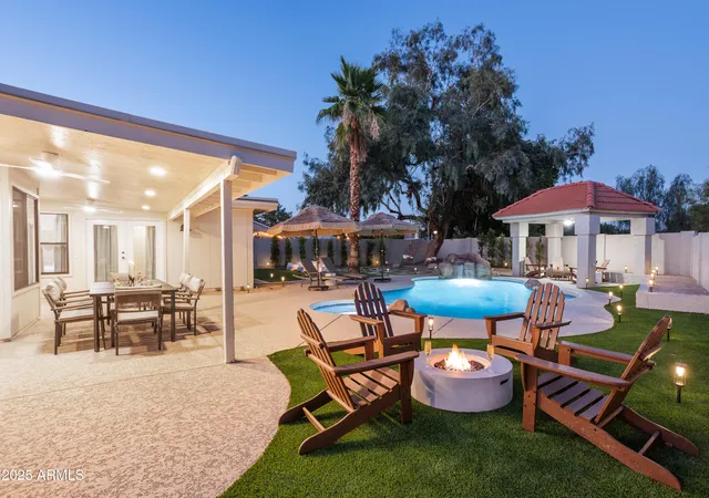 a patio with a table and chairs under an umbrella with a barbeque grill and plants