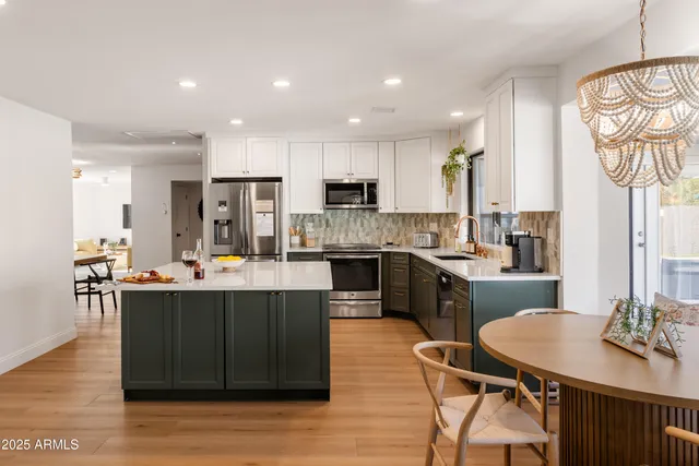 a kitchen with stainless steel appliances kitchen island granite countertop a table chairs and a refrigerator