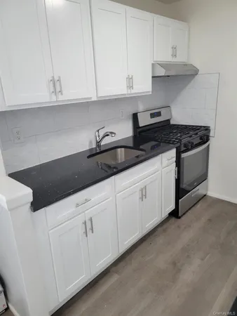 a kitchen with granite countertop white cabinets and a stove