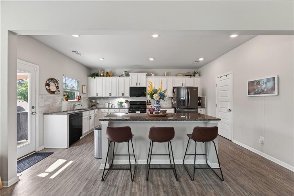 266 Shoals Bridge Road Acworth, GA 30102 - Photo 13 of 43 a kitchen with a sink a refrigerator and chairs with wooden floor
