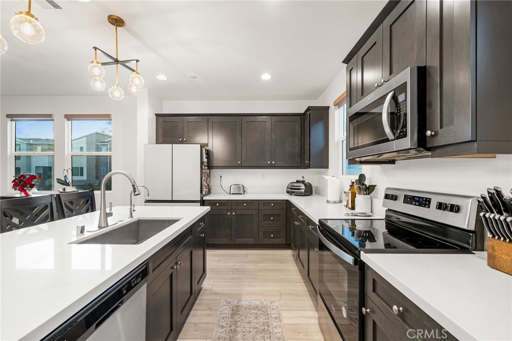 329 North Standard Avenue Santa Ana, CA 92701 - Photo 15 of 34 a kitchen with stainless steel appliances a sink dishwasher a stove top oven a refrigerator with island and chairs