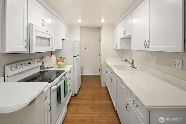 a kitchen with a sink stove top oven and white cabinets