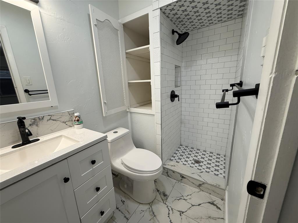 2847 West Rochelle Road Irving, TX 75062 - Photo 13 of 14 a bathroom with a granite countertop sink toilet and shower
