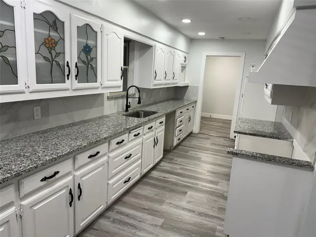 a large kitchen with granite countertop a large counter top and stainless steel appliances