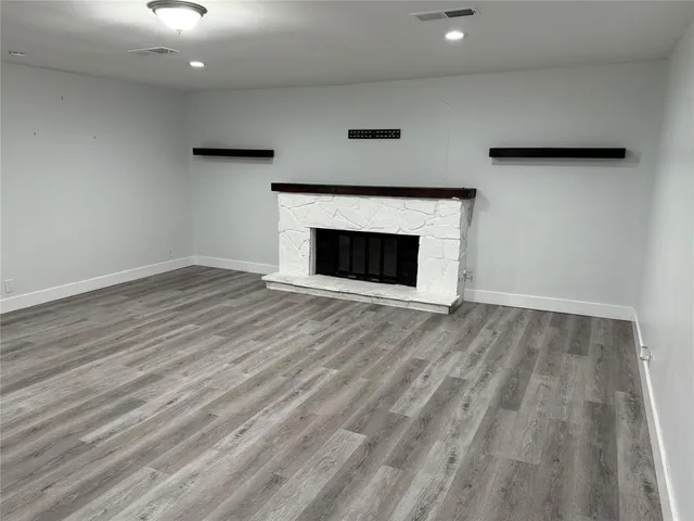 a view of an empty room with wooden floor and a fireplace