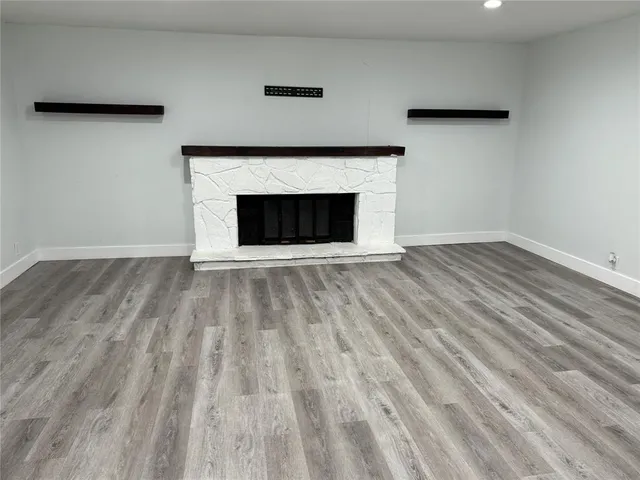 a view of an empty room with wooden floor and a fireplace