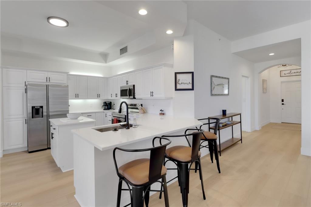 451 Bayfront Place, Unit 5505 Naples, FL 34102 - Photo 2 of 23 a kitchen with stainless steel appliances kitchen island granite countertop a dining table chairs and a refrigerator