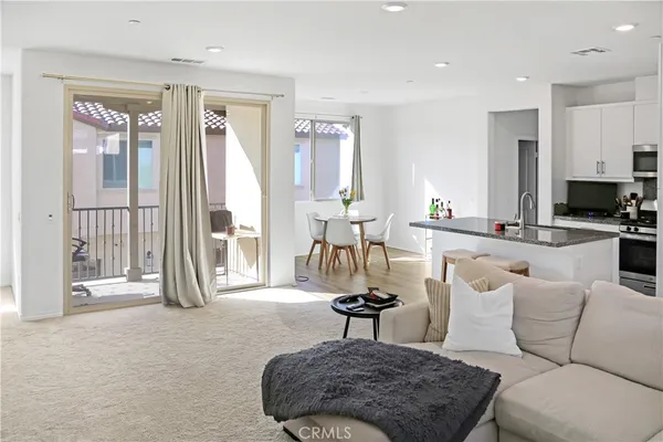 a living room with furniture a large window and kitchen view