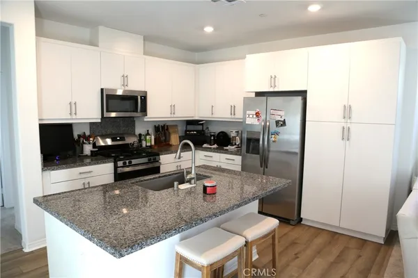 a large white kitchen with lots of counter space wooden cabinets and stainless steel appliances