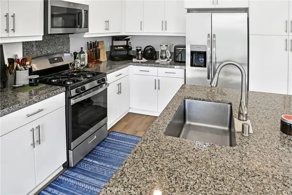 a kitchen with stainless steel appliances granite countertop a sink refrigerator and microwave
