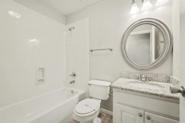 a bathroom with a granite countertop toilet a sink and a bathtub