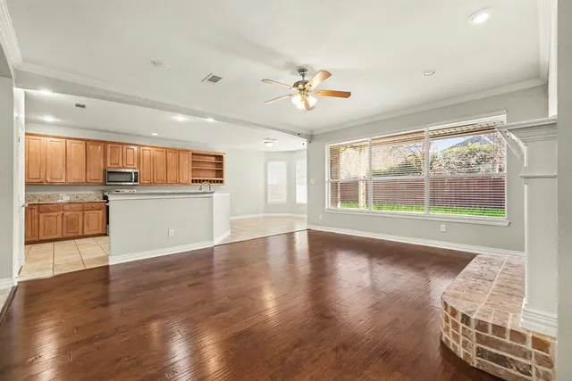 a view of an empty room with a window and wooden floor
