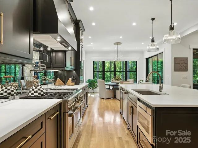 a kitchen with stainless steel appliances granite countertop a sink a stove and a wooden floors