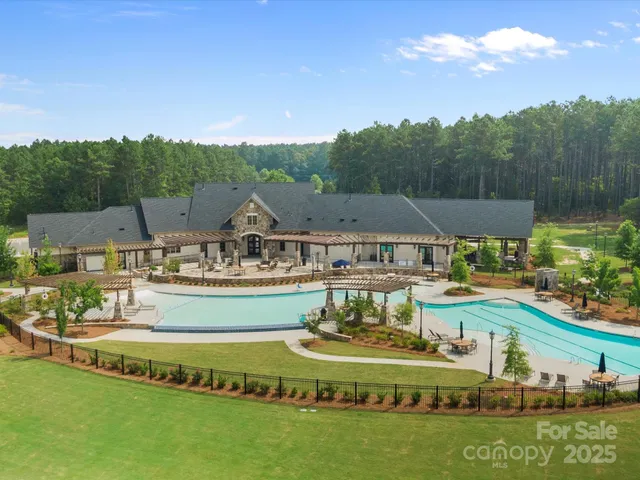 a view of swimming pool with outdoor seating and trees in the background