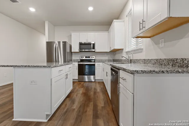 a kitchen with stainless steel appliances granite countertop a sink stove refrigerator and cabinets