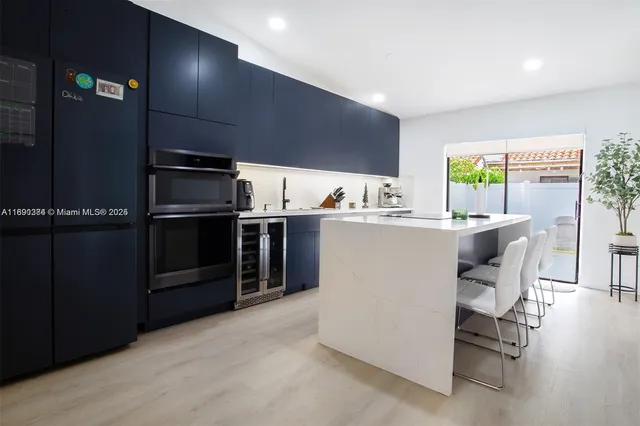 a kitchen with kitchen island stainless steel appliances a sink cabinets and a window