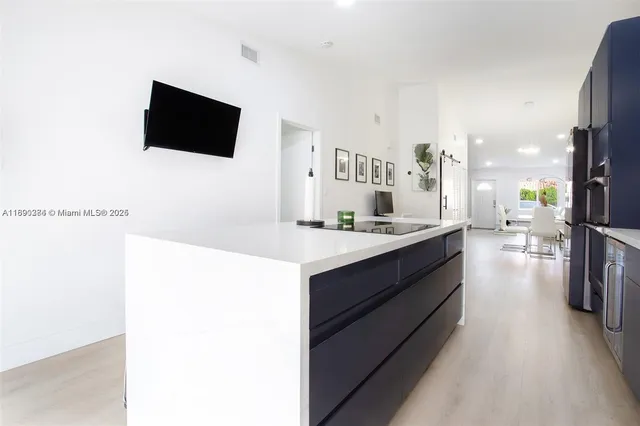 a large white kitchen with a sink and a large mirror