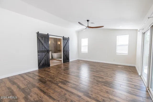 an empty room with wooden floor and windows
