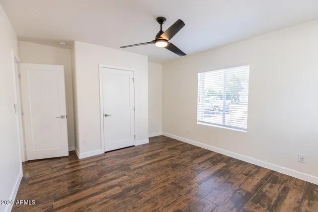 a view of empty room with wooden floor and ceiling fan