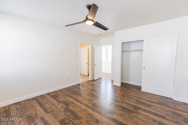 a view of a room with wooden floor ceiling fan and window
