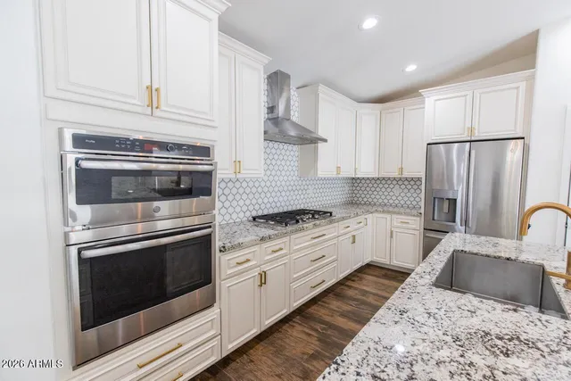 a kitchen with stainless steel appliances granite countertop a stove a sink and a refrigerator