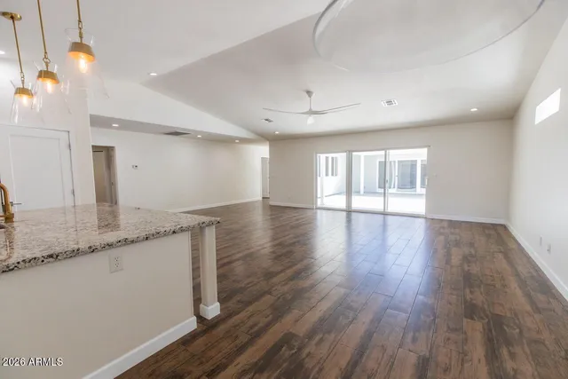 a large kitchen with granite countertop a large window and wooden floor