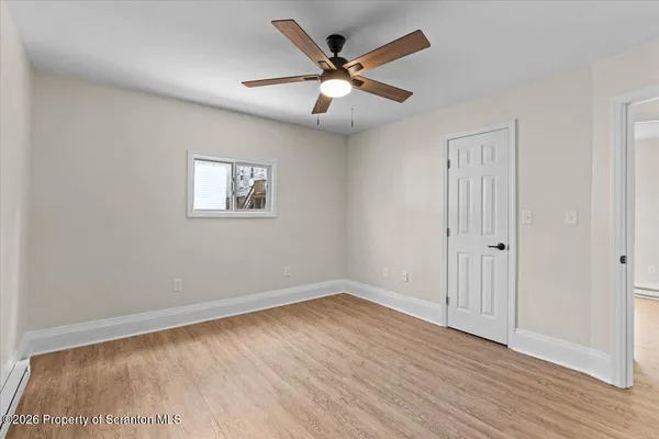 an empty room with wooden floor and ceiling fan