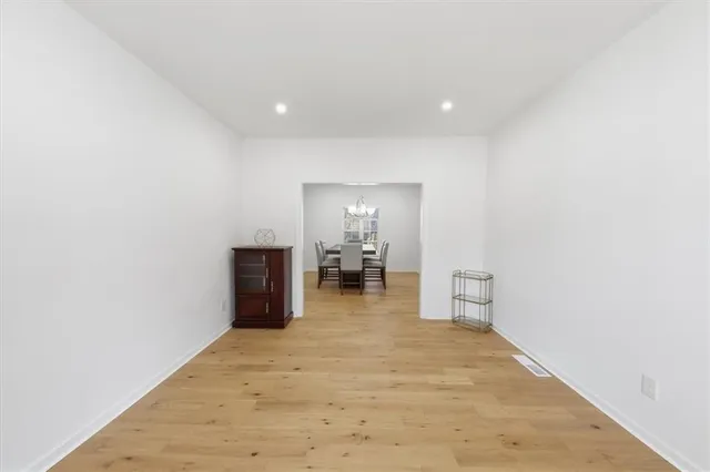 a view of a hallway with wooden floor and a bathroom