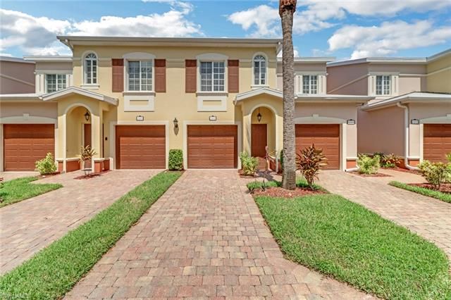 a front view of a house with yard and parking