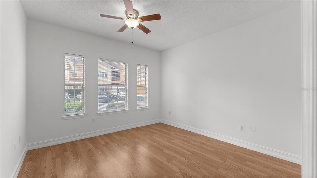 12204 Wild Iris Way, Unit 103 Orlando, FL 32837 - Photo 13 of 22 an empty room with wooden floor ceiling fan and windows