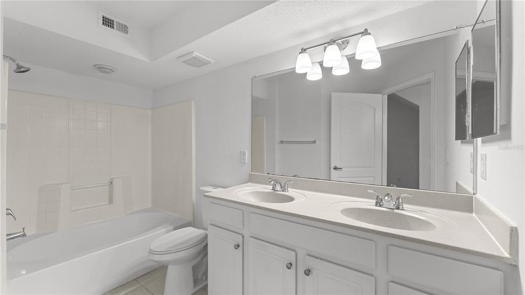 12204 Wild Iris Way, Unit 103 Orlando, FL 32837 - Photo 19 of 22 a bathroom with a sink a toilet and a mirror