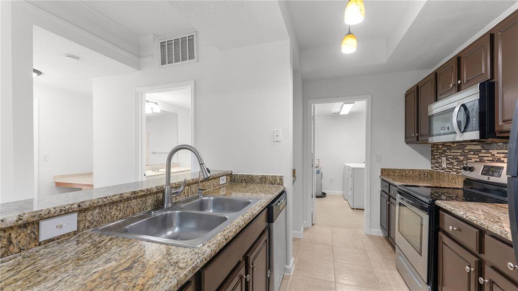 12204 Wild Iris Way, Unit 103 Orlando, FL 32837 - Photo 8 of 22 a kitchen with granite countertop a sink stove and cabinets
