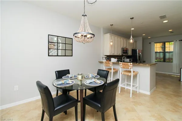 a dining room with furniture a chandelier and kitchen view