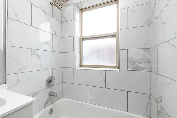 a bathroom with a bathtub and next to a window