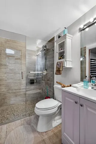 a bathroom with a granite countertop toilet a sink a mirror and shower