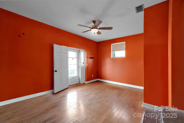 a view of an empty room with window and wooden floor