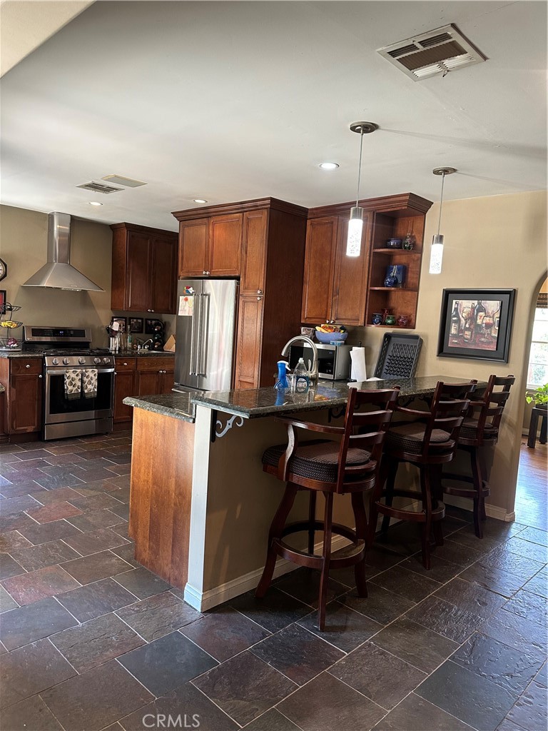 4910 Willowcrest Avenue Toluca Lake, CA 91601 - Photo 11 of 25 a kitchen with stainless steel appliances kitchen island granite countertop a table chairs sink and refrigerator