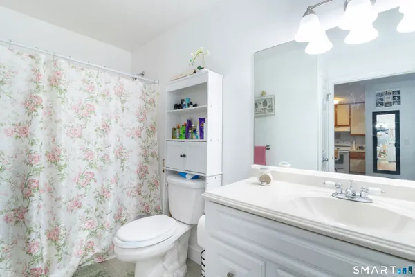 a bathroom with a granite countertop toilet a sink and a mirror