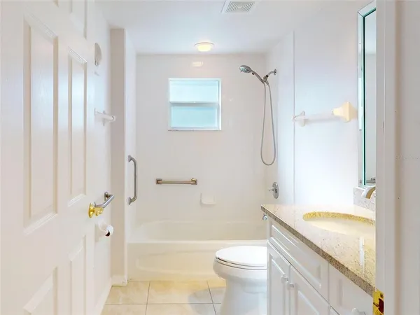 a spacious bathroom with a granite countertop sink a toilet a mirror and shower