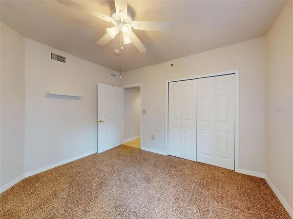 an empty room with closet and a chandelier fan