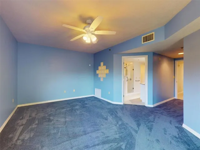 a view of an empty room with window and chandelier fan