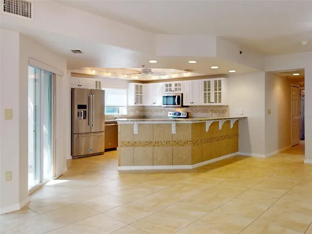 a view of a kitchen with stainless steel appliances granite countertop a stove top oven a refrigerator and a sink