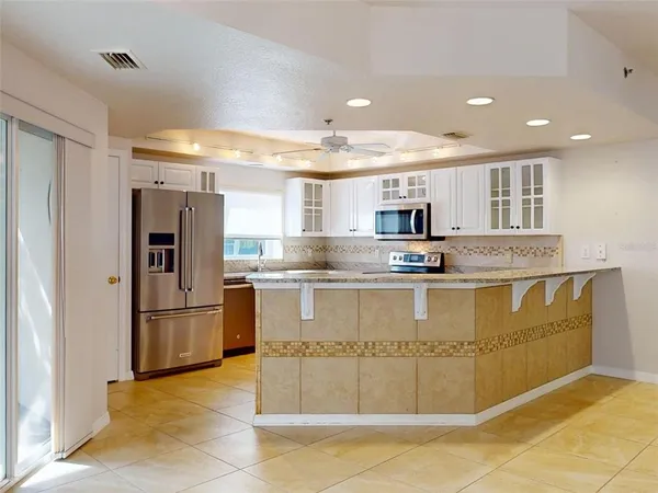 a view of a kitchen with stainless steel appliances granite countertop a stove and a refrigerator
