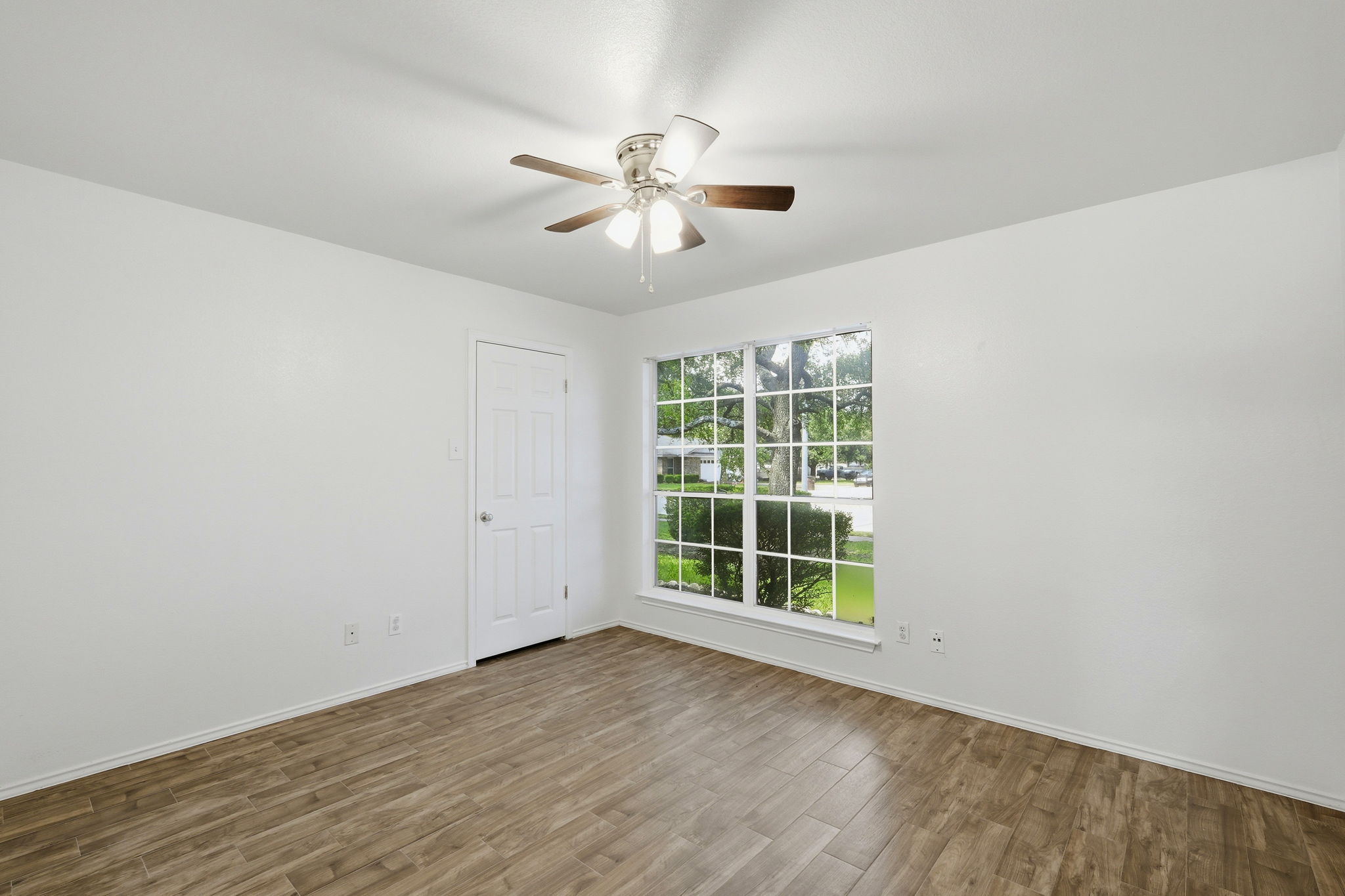 1005 Rolling Ridge Drive Round Rock, TX 78665 - Photo 12 of 18 Well-lit room with wood-look flooring, featuring a large window and overhead fan for optimal comfort.