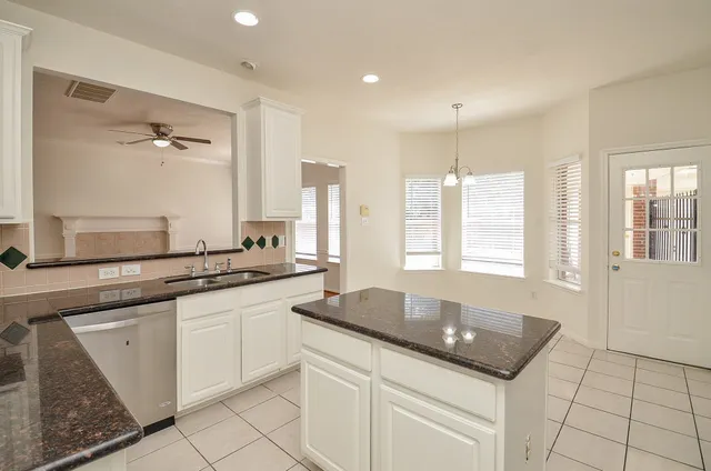 a kitchen with granite countertop a sink and white cabinets