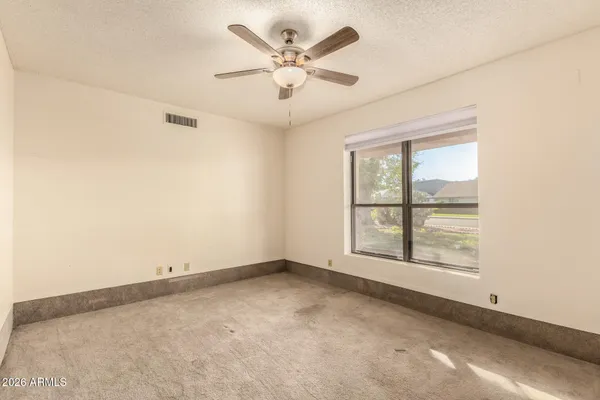 an empty room with windows and ceiling fan